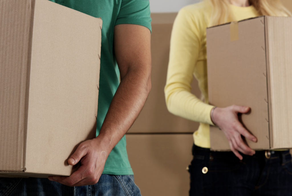 Two people holding cardboard boxes, possibly moving or delivering items.
