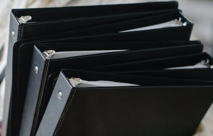 Stack of black binders with papers, arranged in a neat order.