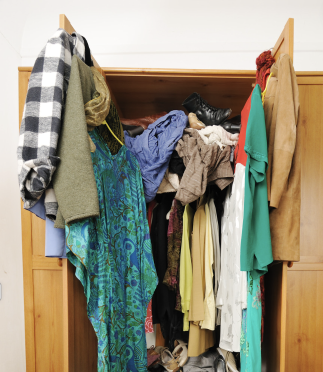 An overstuffed wardrobe with clothes and accessories spilling out.