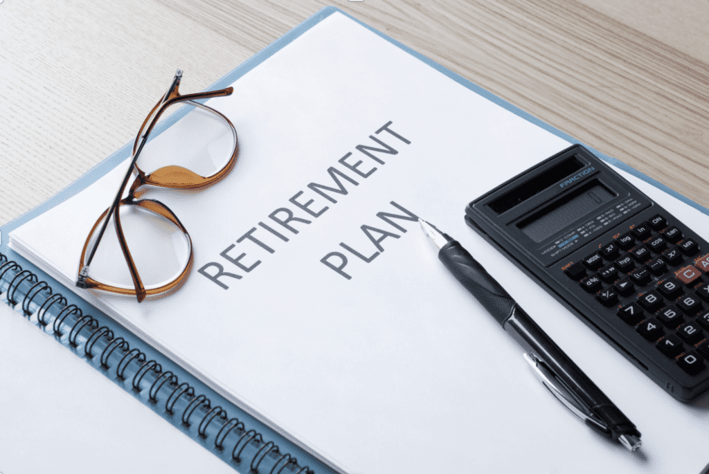 A retirement plan document with a pair of glasses, a pen, and calculator on a desk.
