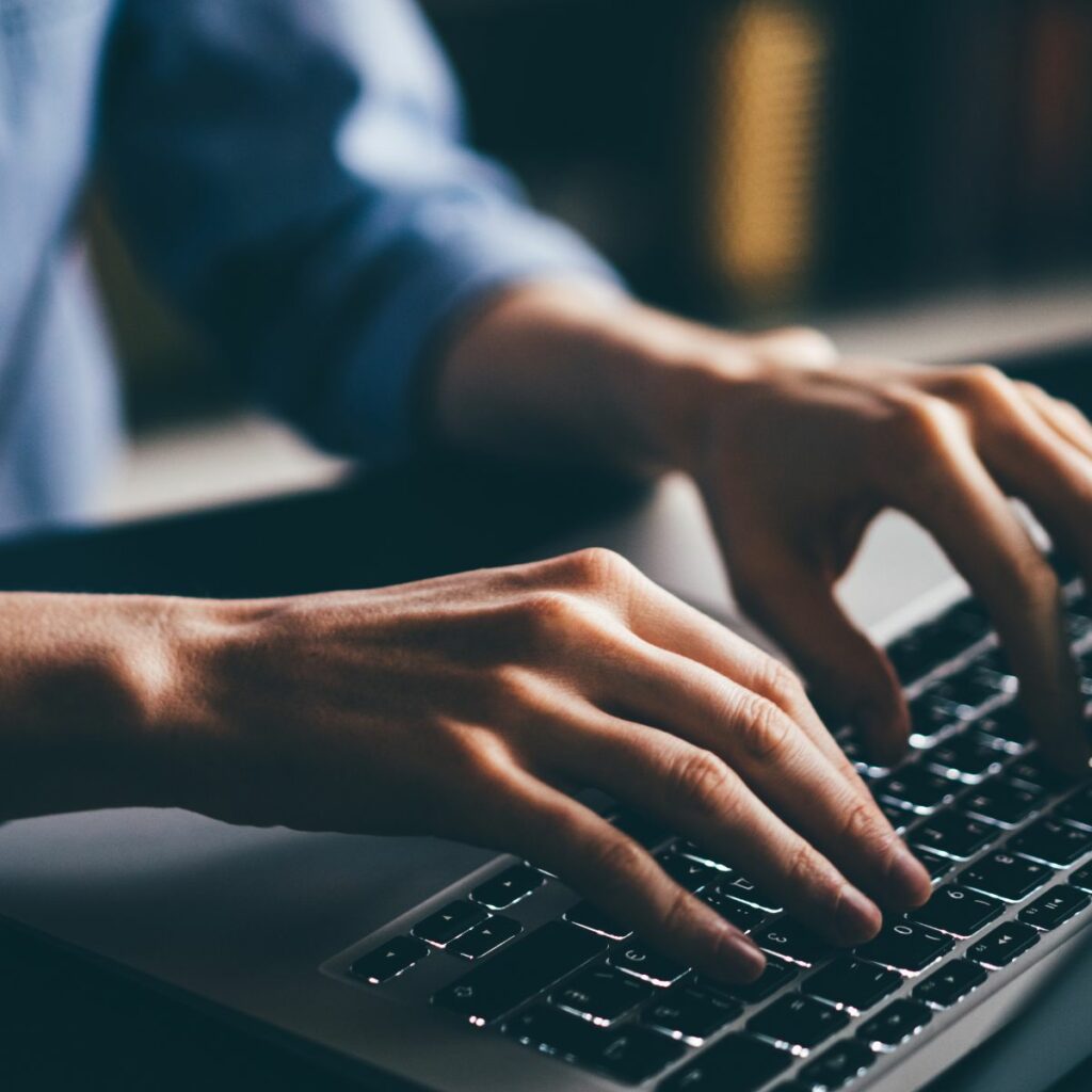 Close-up of a person typing on a laptop keyboard, showcasing hybrid working.
